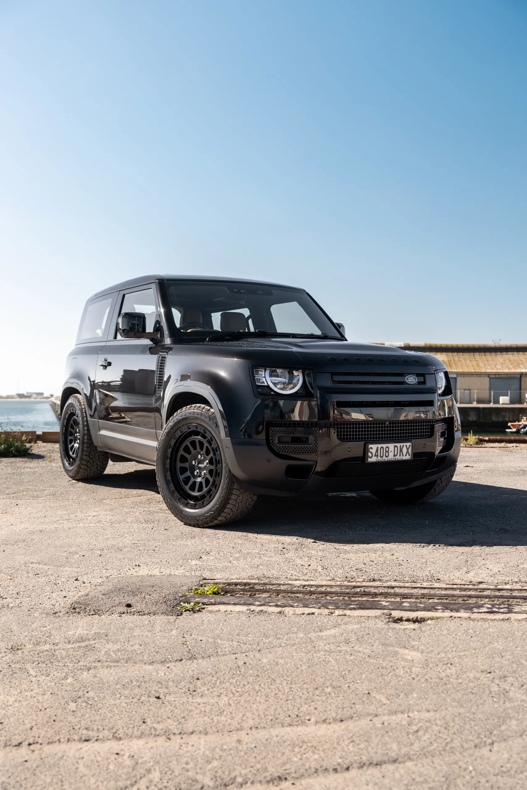 Black Land Rover Defender 90 with 20x9 +22 5x120 Matte Black ROH Assault Wheels at dockyard