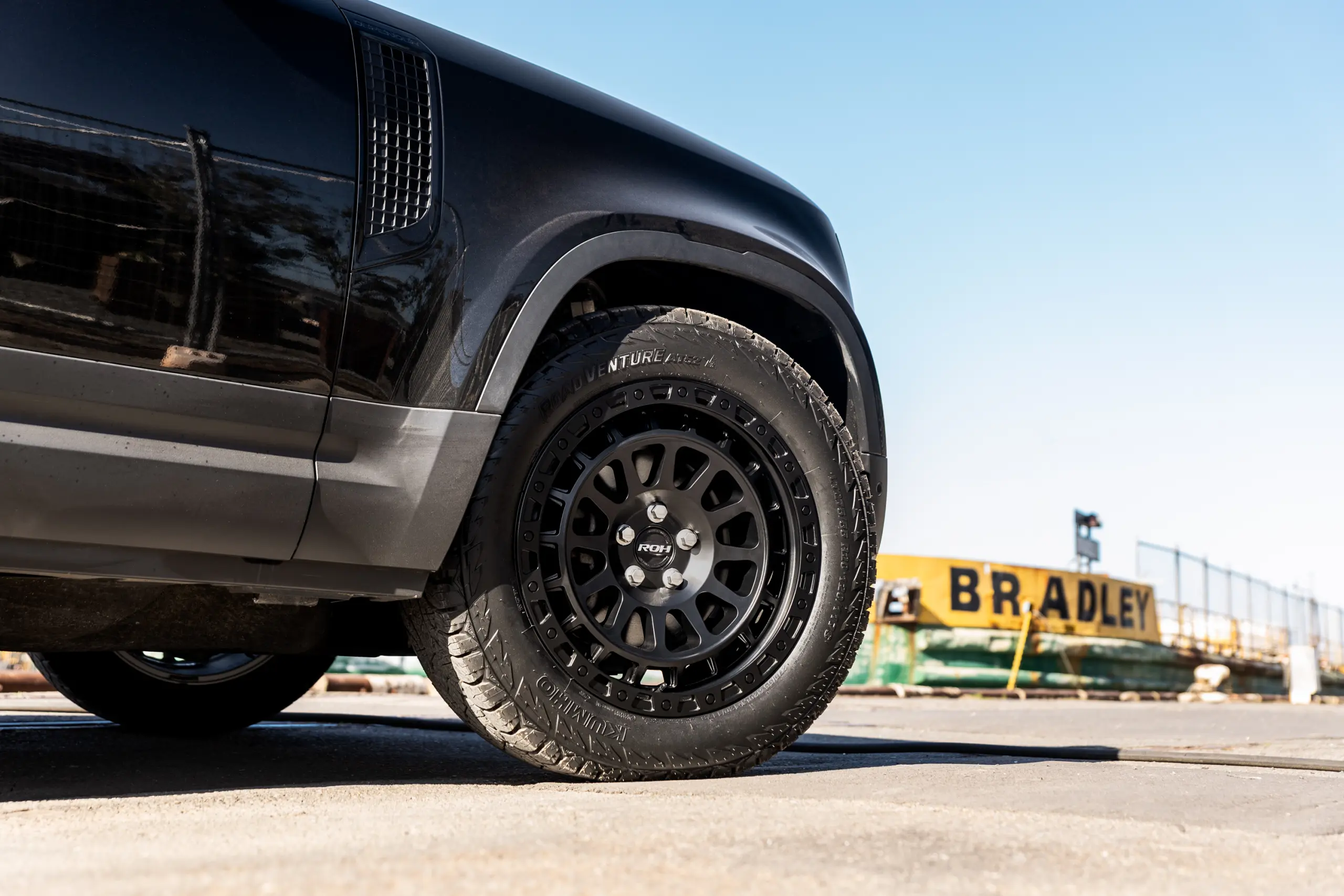 Black Land Rover Defender 90 with 20x9 +22 5x120 Matte Black ROH Assault Wheels at dockyard