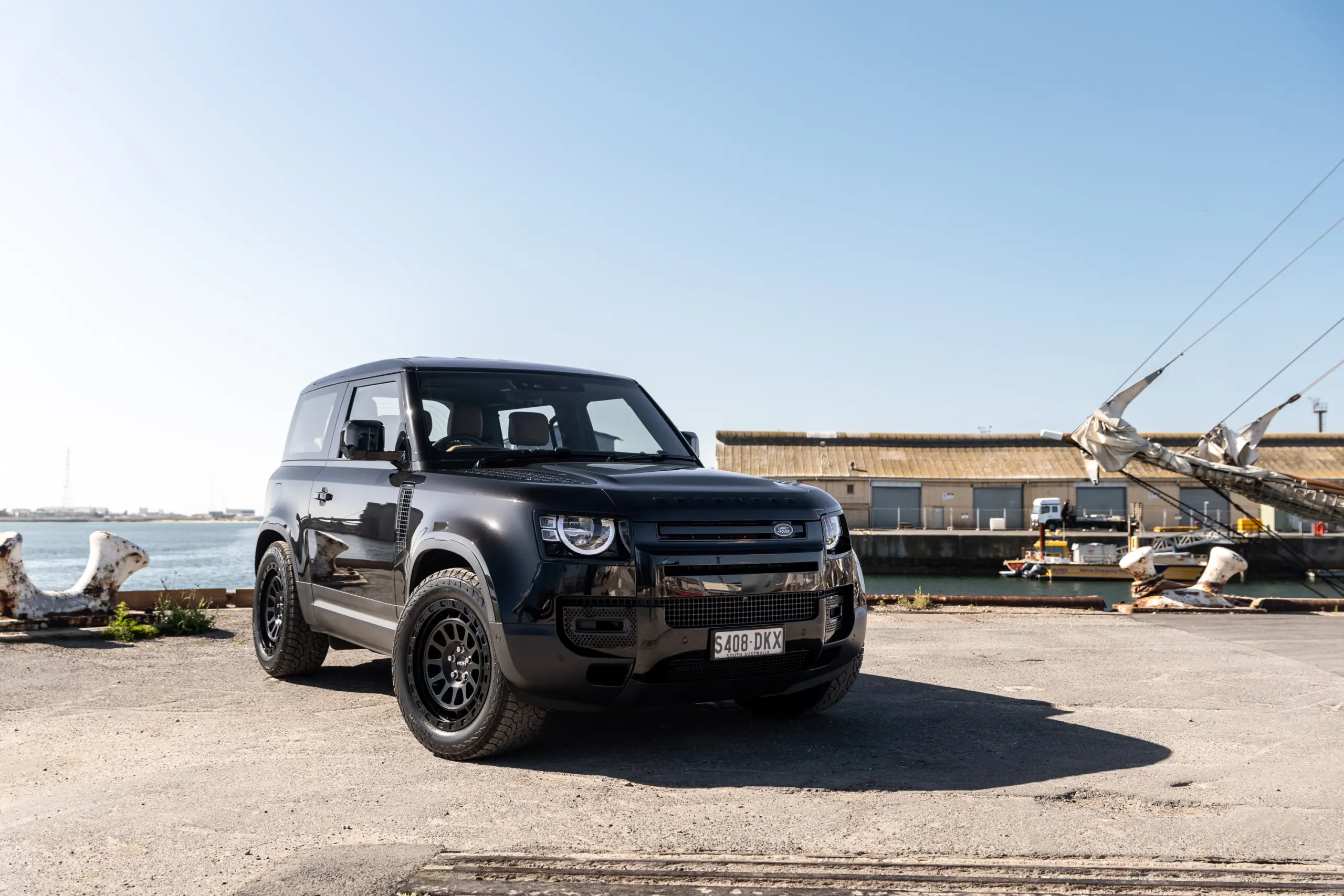 Black Land Rover Defender 90 with 20x9 +22 5x120 Matte Black ROH Assault Wheels at dockyard