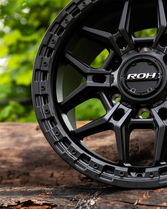 ROH Axe Matte Black 4x4 Alloy Wheel on wood logs