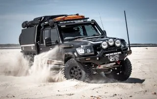 Black Octagon Wheels on Toyota Landcruiser 79 series on beach kicking up sand header