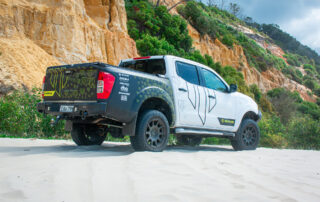 NP300 4x4 wheels on Whiteline Navara in front of sand cliff face