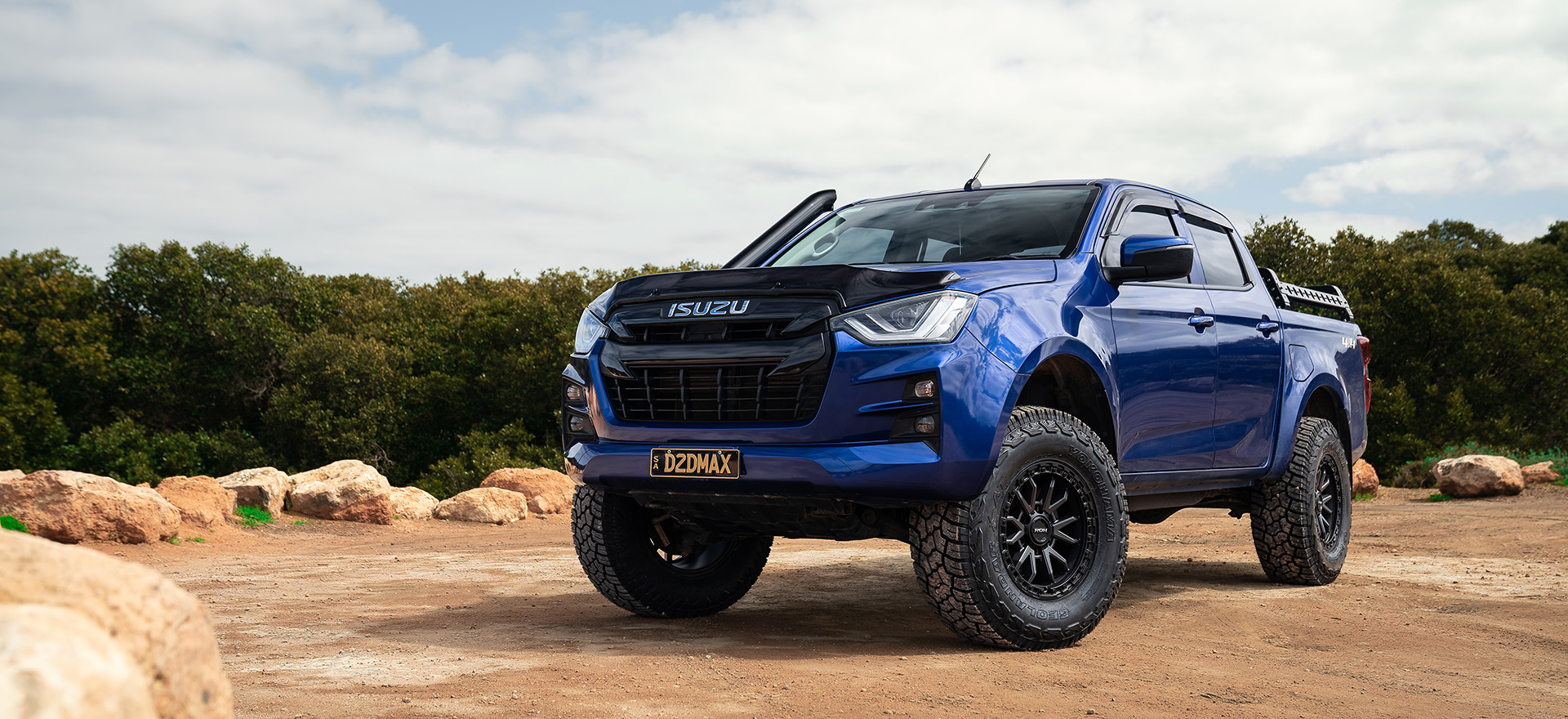 Raid wheels on blue hero Isuzu D-Max in front of rocks with mangroves