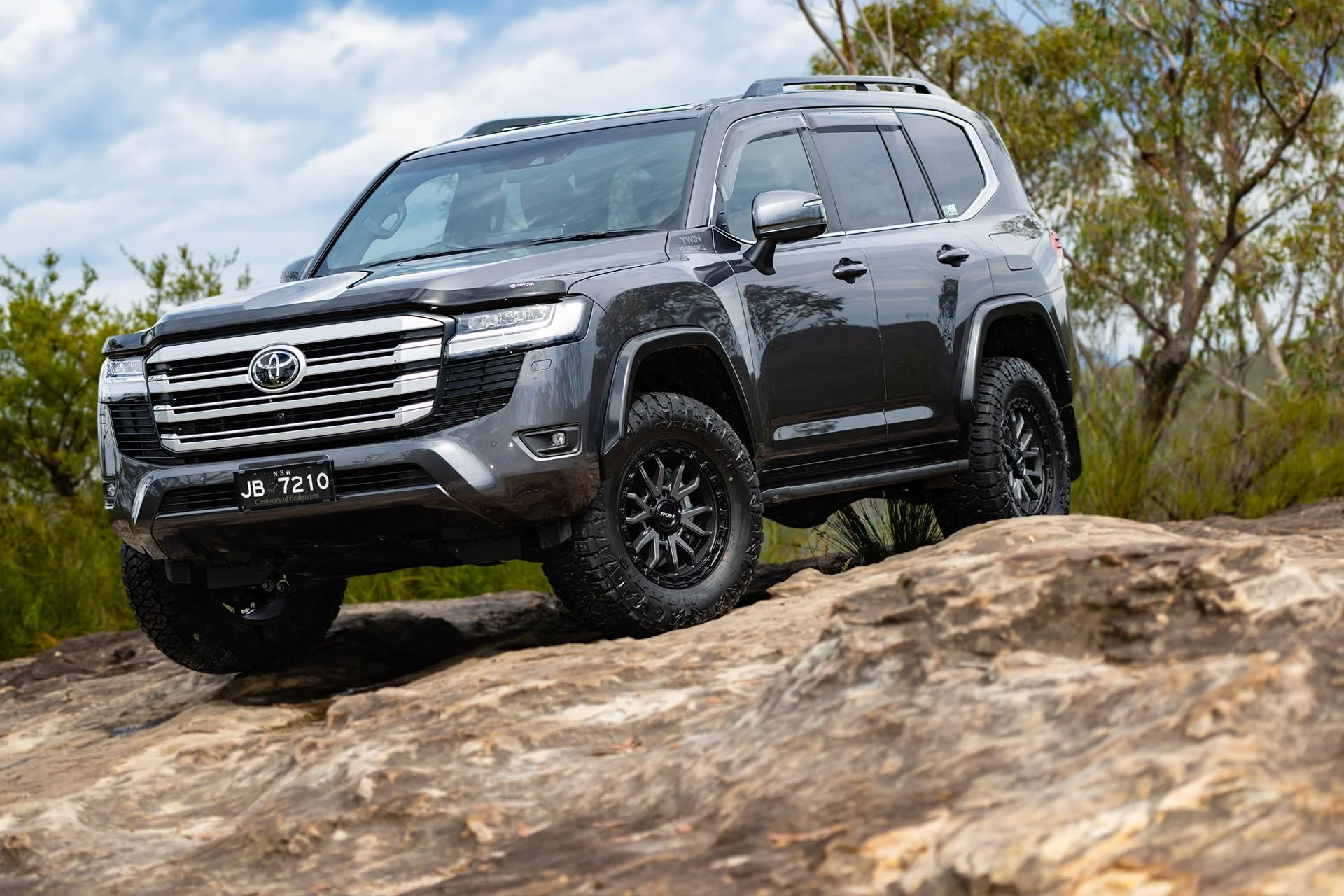 Raid wheels on Grey LC300 on rocky outcrop in the bush